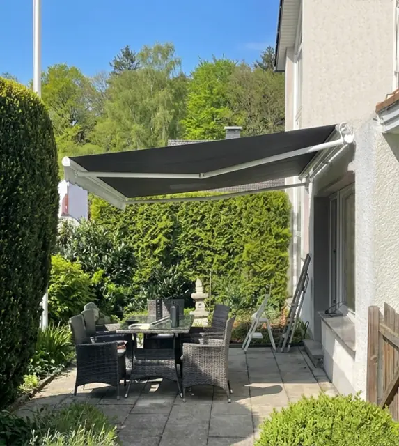 Installed solar awning with folding arms over a garden terrace
