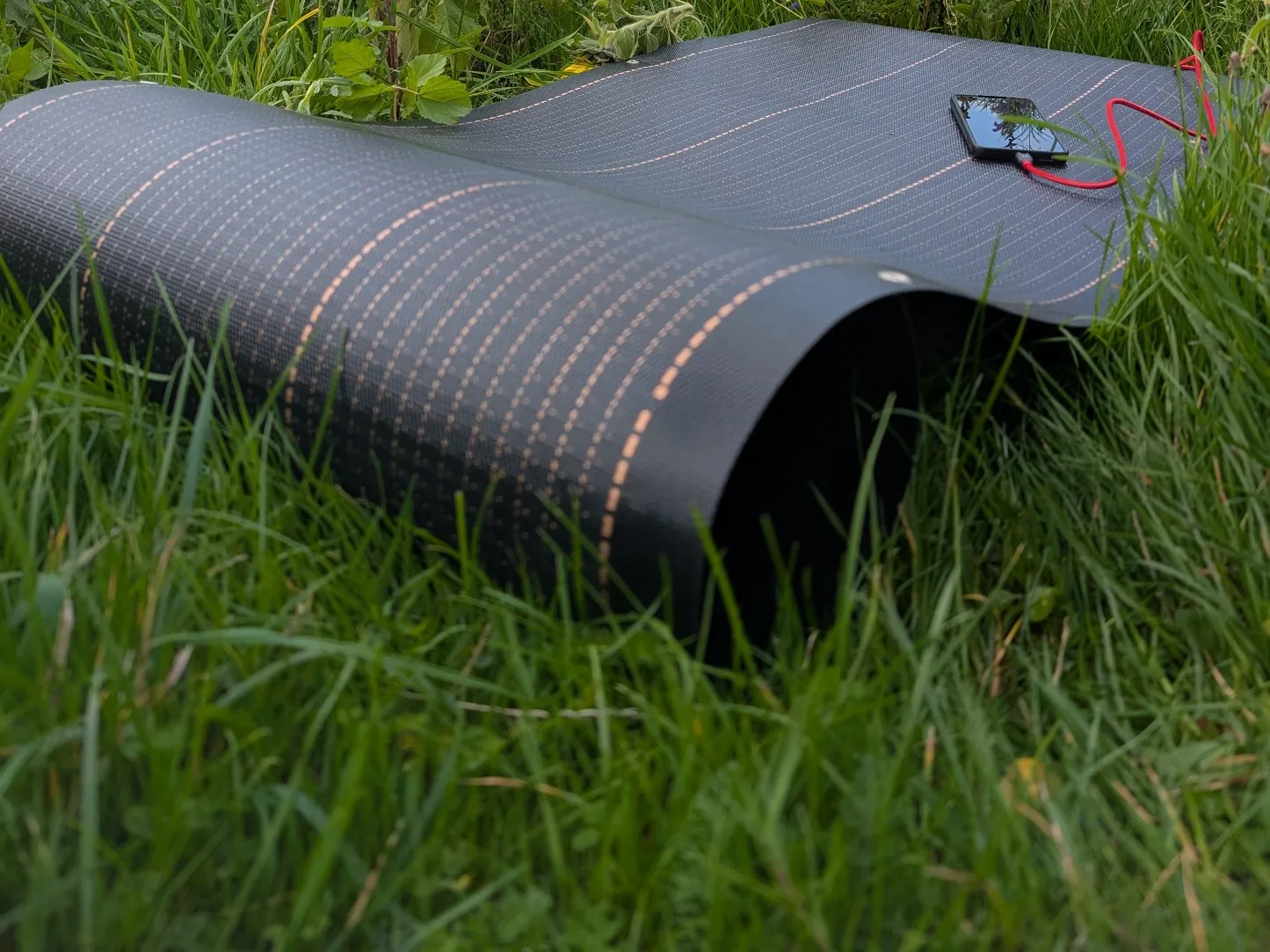 Flexible photovoltaic solar awning fabric charging a phone